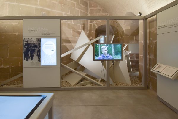 Kunstinstallation aus Trümmern mit Medienstationen im Ausstellungsraum.